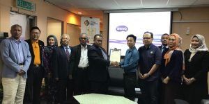 A group of people in a meeting room, posing for a photo in front of a projector screen with the BenQ logo.