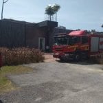Fire truck parked outside a dark building. The scene is outdoors on a sunny day.