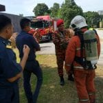 Firefighters and others standing near a fire truck, possibly discussing the situation outdoors.