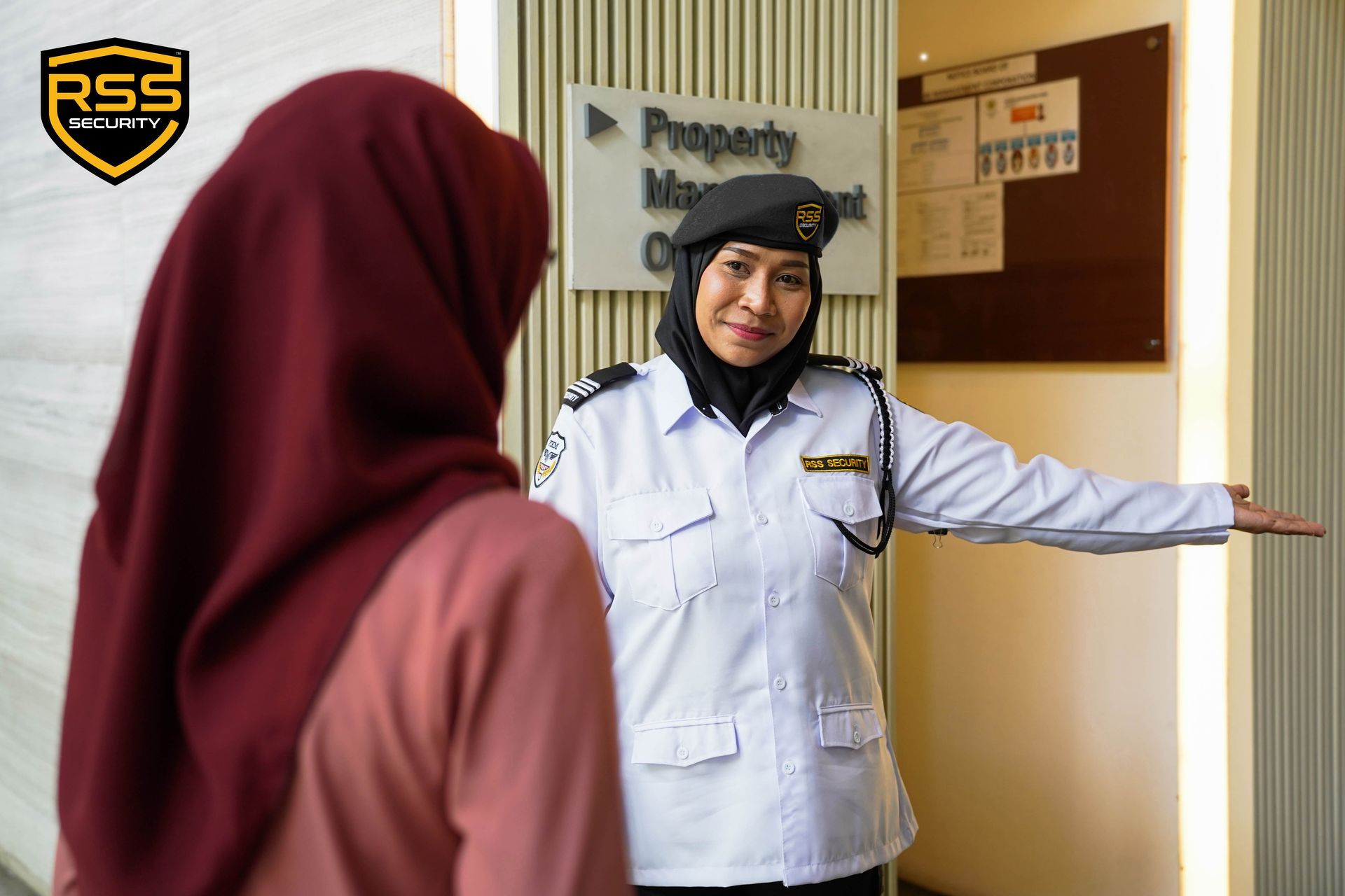 A supervisor in a black uniform briefing four security personnel in white shirts and black trousers in an outdoor lot.