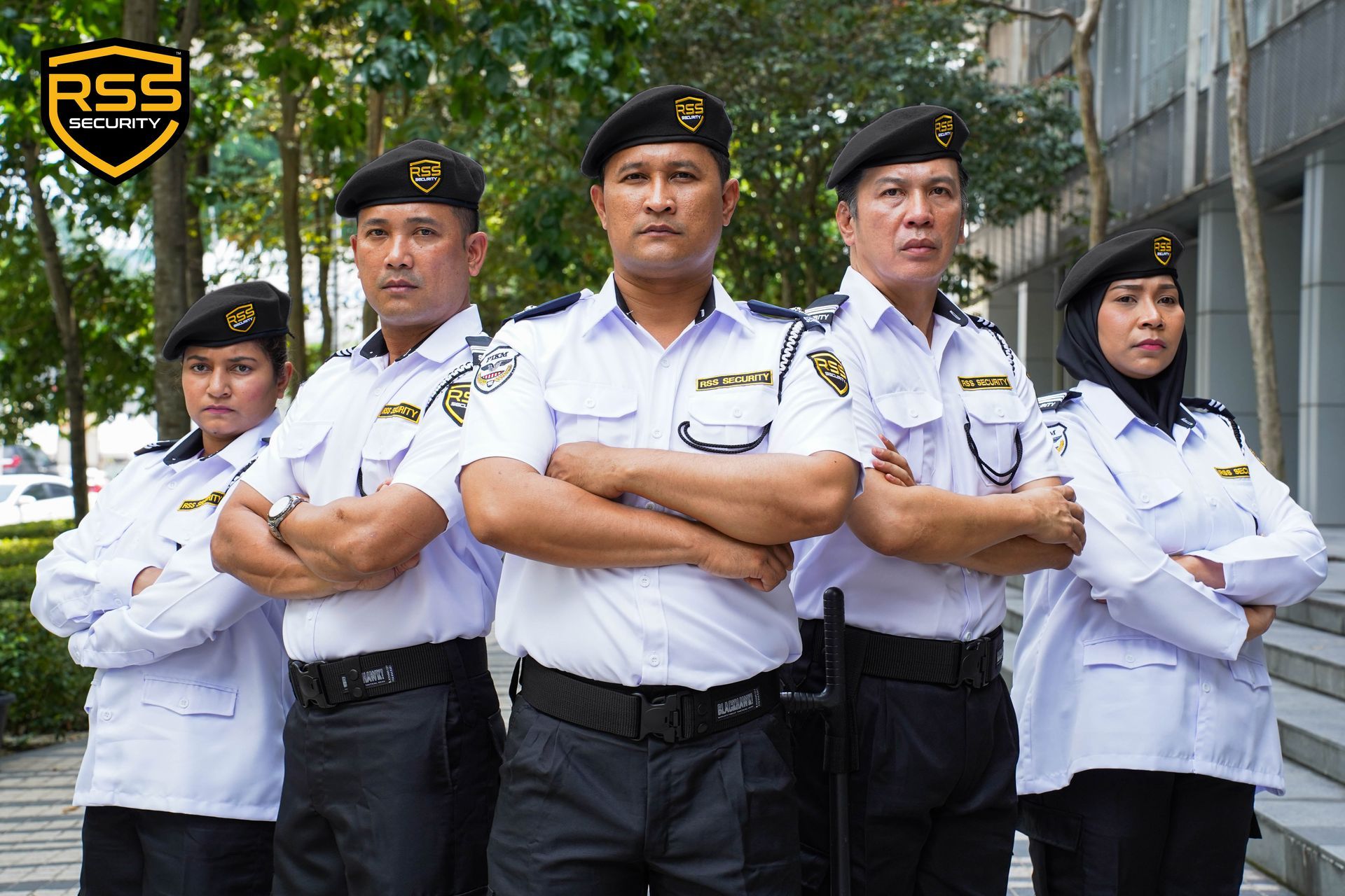 Five security personnel in white uniforms and black berets stand with arms crossed in front of a building.