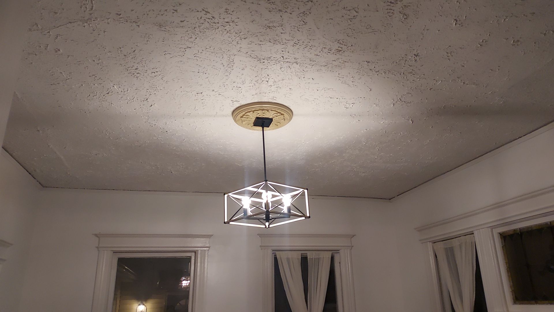A person installing a chrome shower valve handle onto a tiled shower wall.
