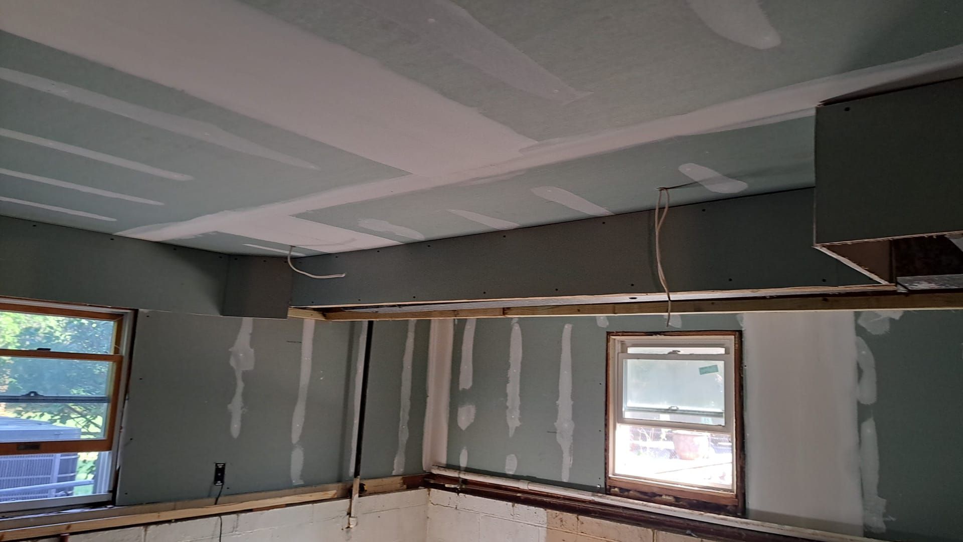 A person in workwear uses a power jigsaw to cut a curved line into a piece of wood, with sawdust visible in the air.