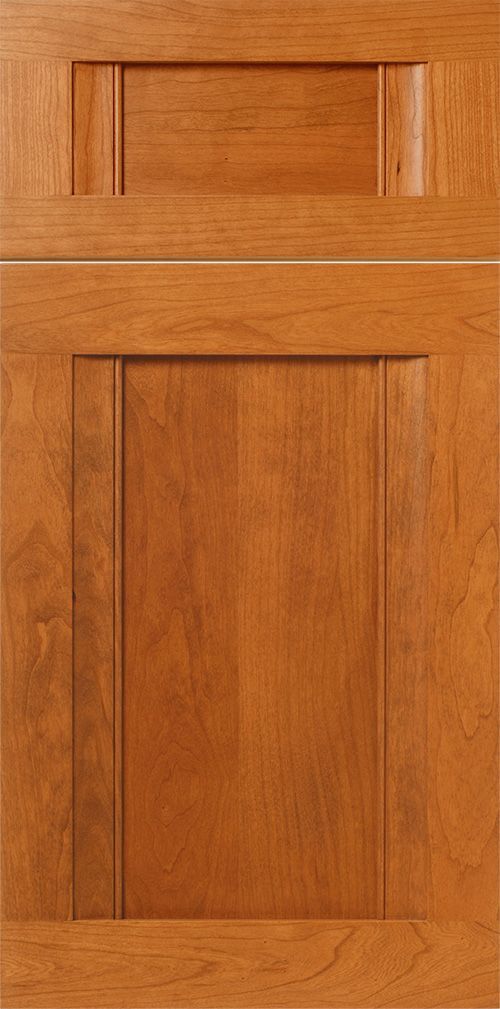 Close-up of a wood kitchen cabinet door with a raised panel design in a light brown stain.