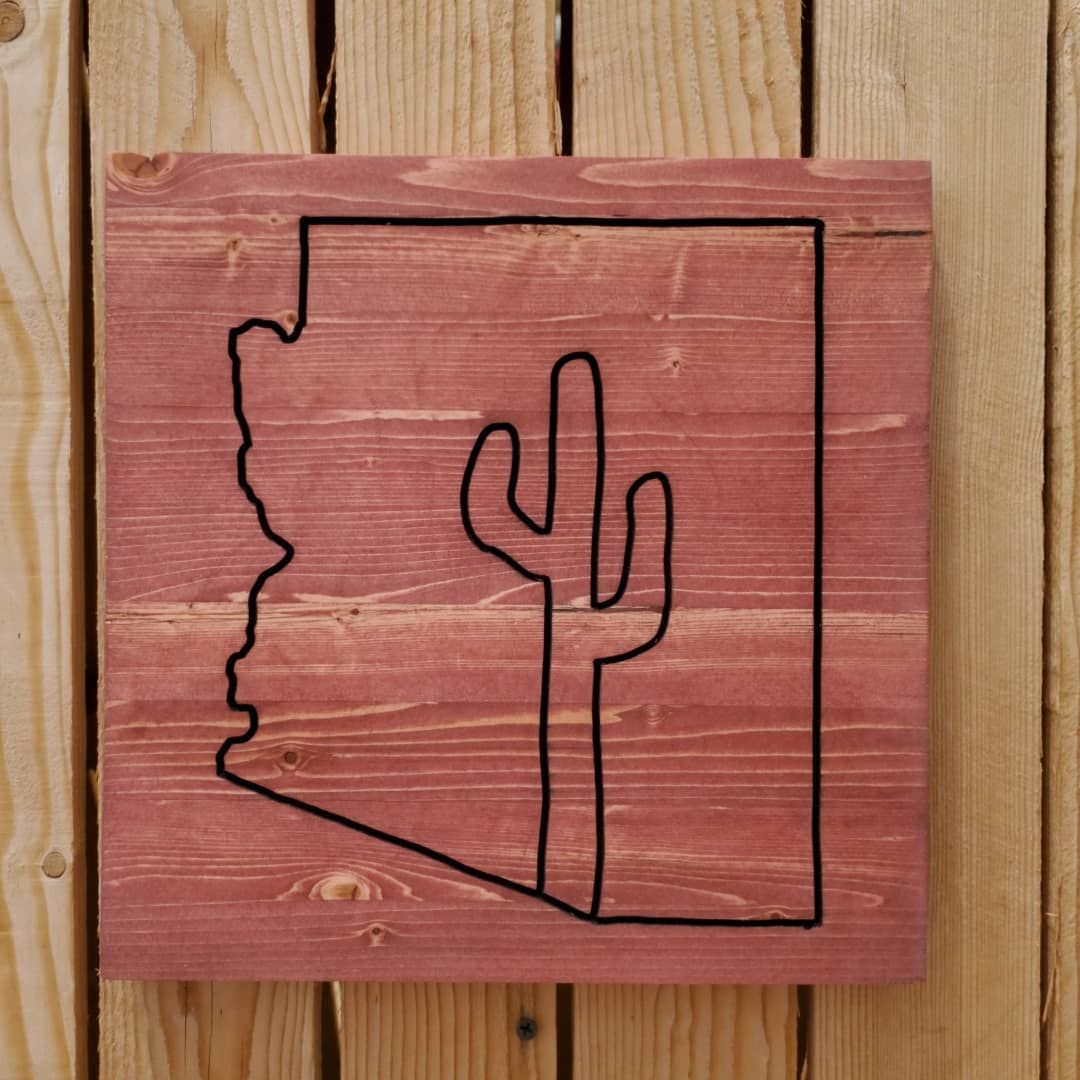 Arizona state outline and cactus design on stained wood.