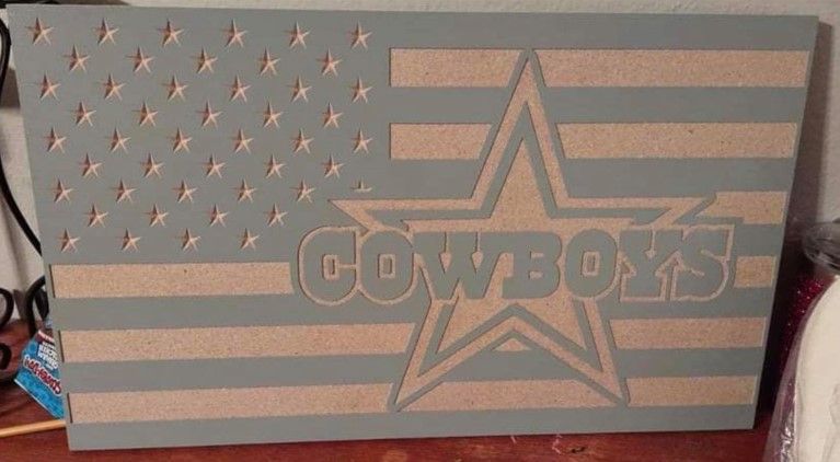 Gray wooden carving of the American flag and Dallas Cowboys logo.