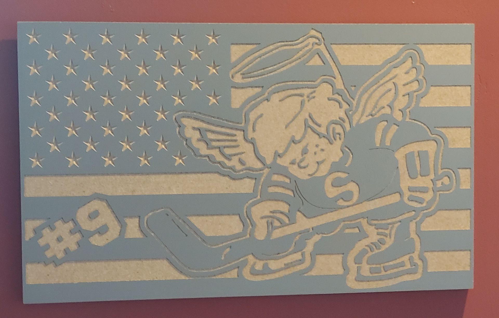 American flag with a cartoon hockey-playing angel, wearing jersey number 9.