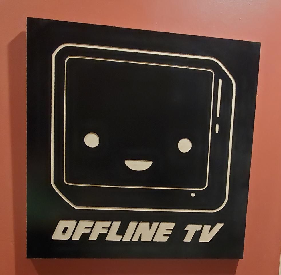 A black sign with a smiling cartoon TV with the text