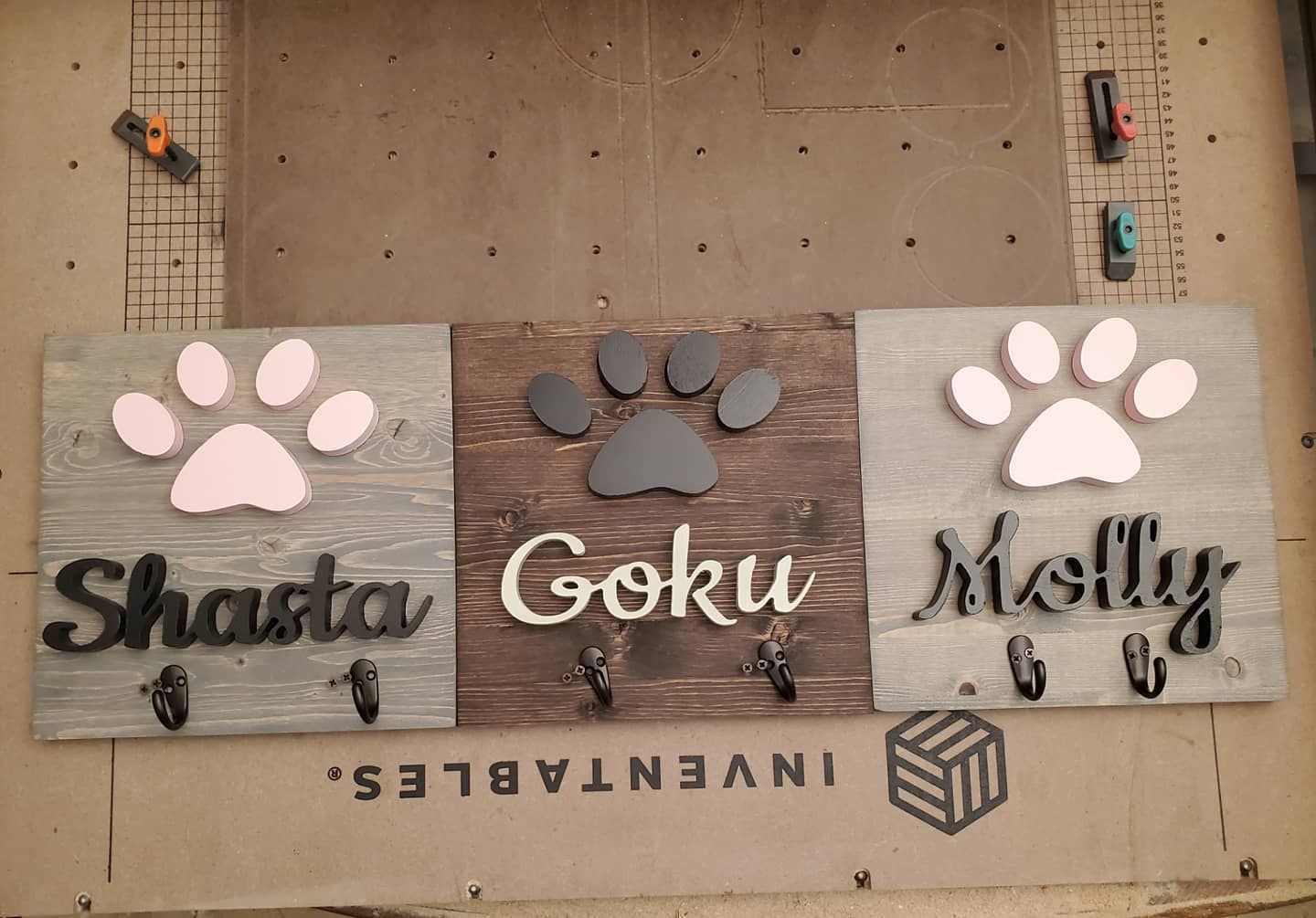 Three dog leash holders with names and paw prints.