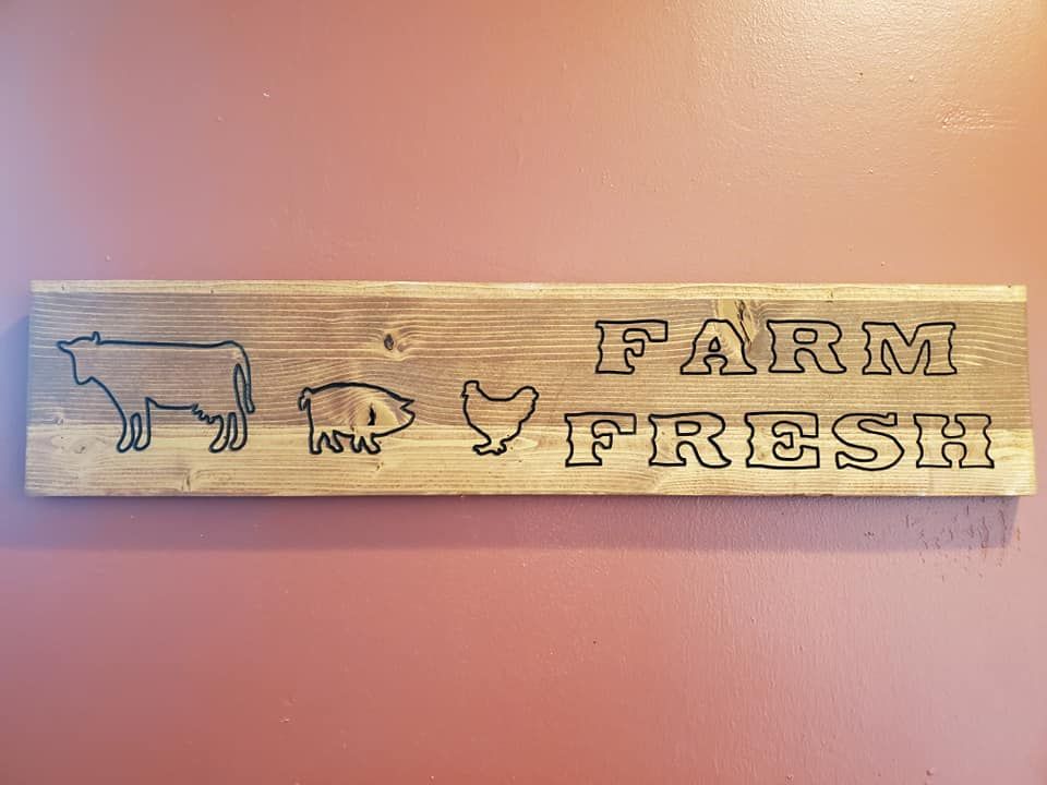 Wooden sign with a cow, pig, and chicken beside