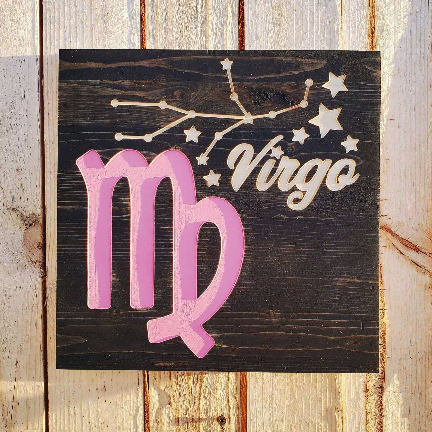 Wooden sign with a pink Virgo symbol, constellation, and text on a black background.