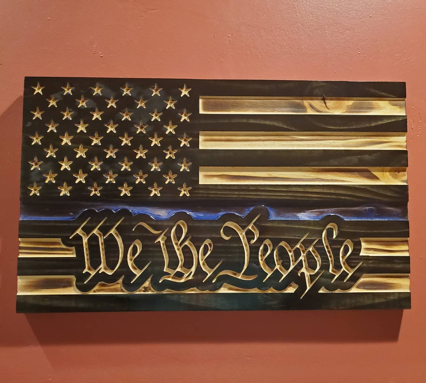 Wooden art piece depicting the American flag with a thin blue line and