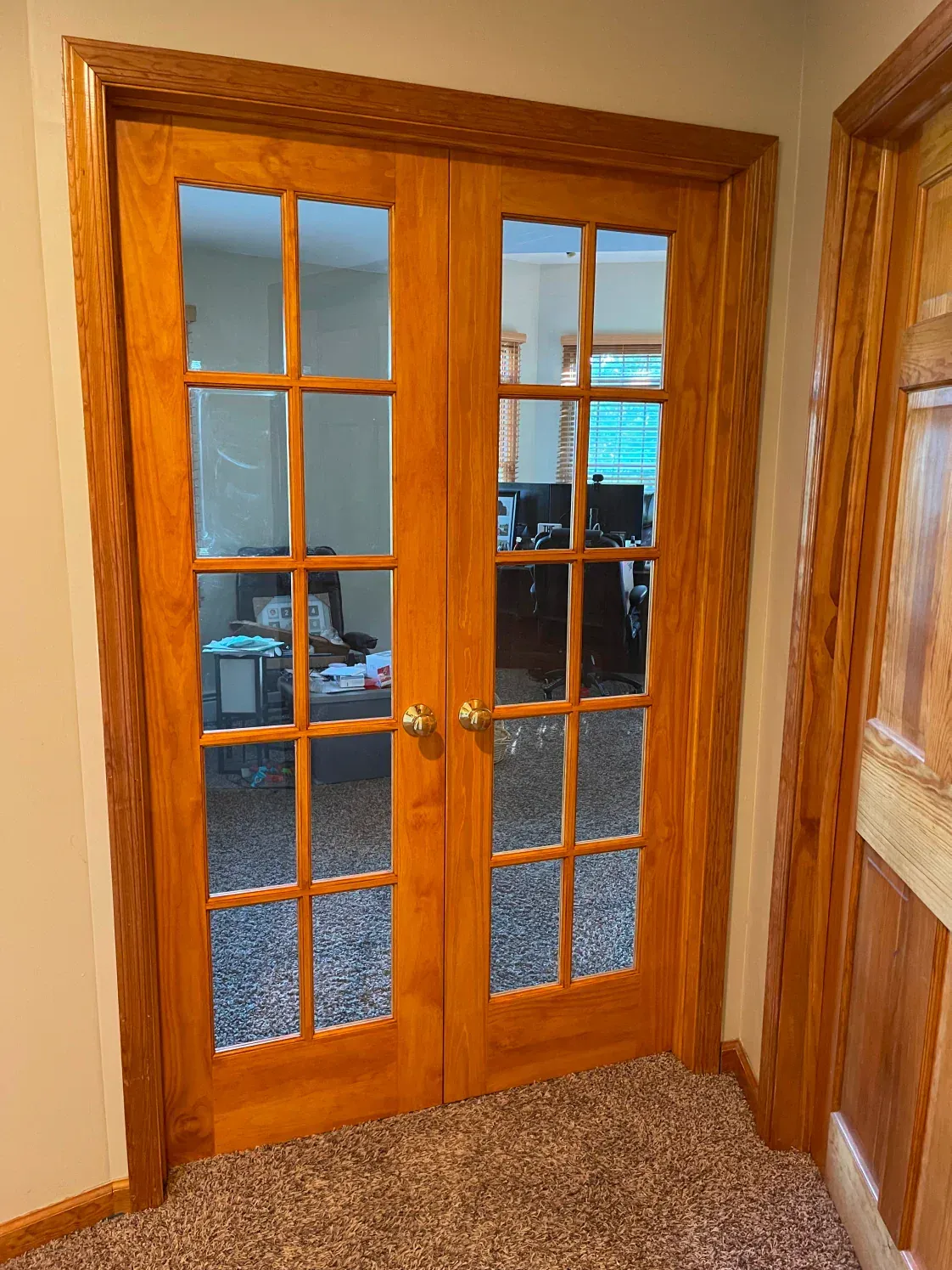 Wooden French doors with glass panes, leading to an office.