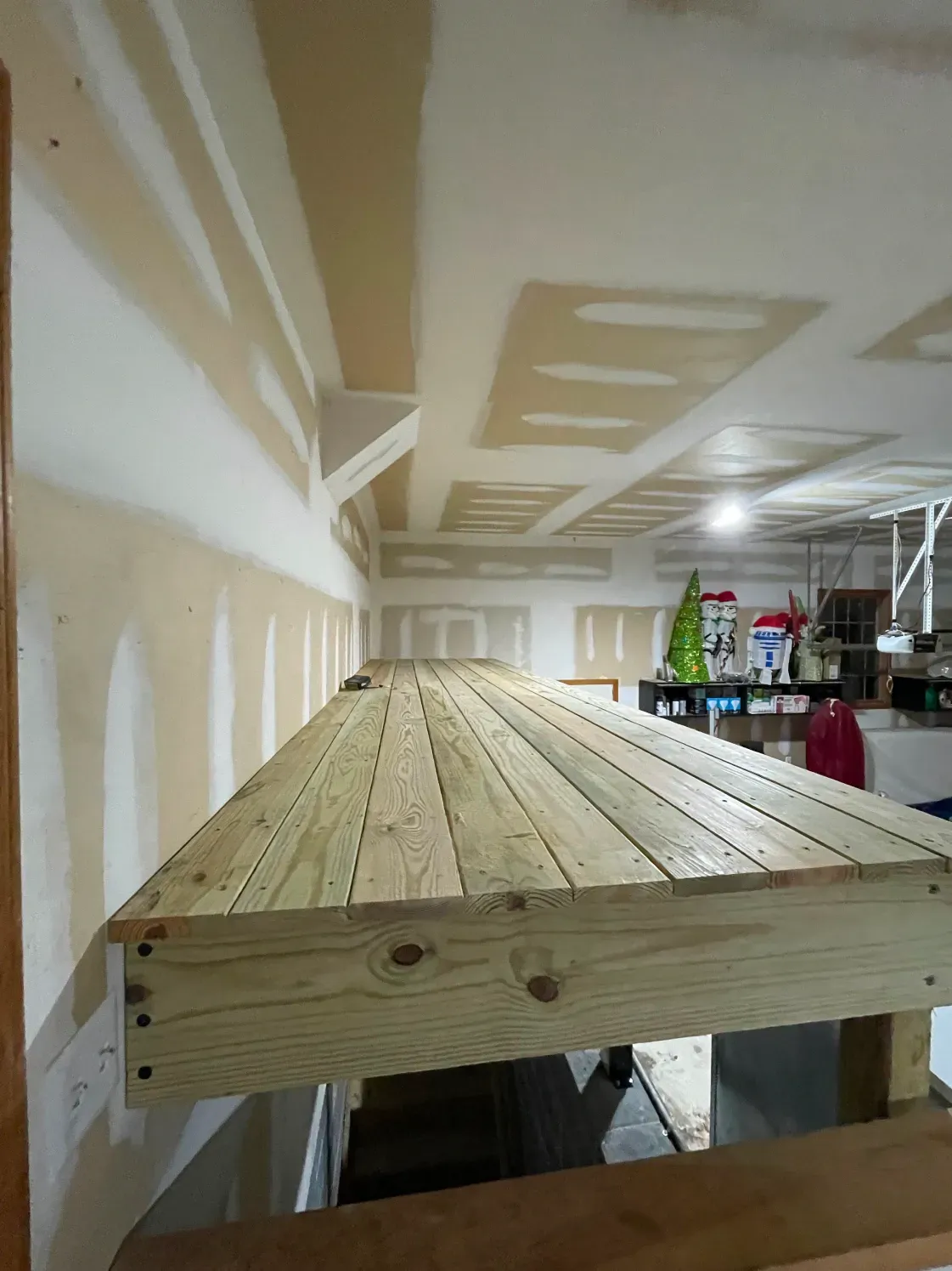 Wooden platform under a ceiling. Boards are light brown, walls are white and beige.