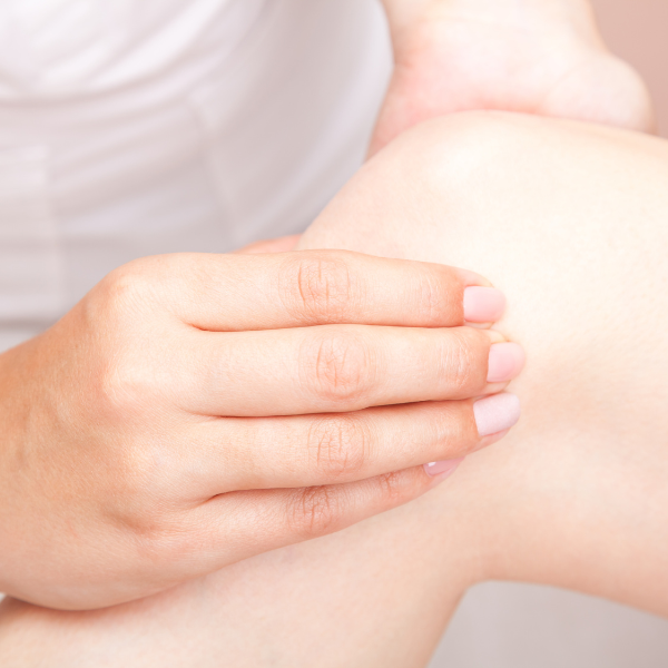 Sandstone Therapeutic Massage / A woman with her knee being worked on by a massage therapist.