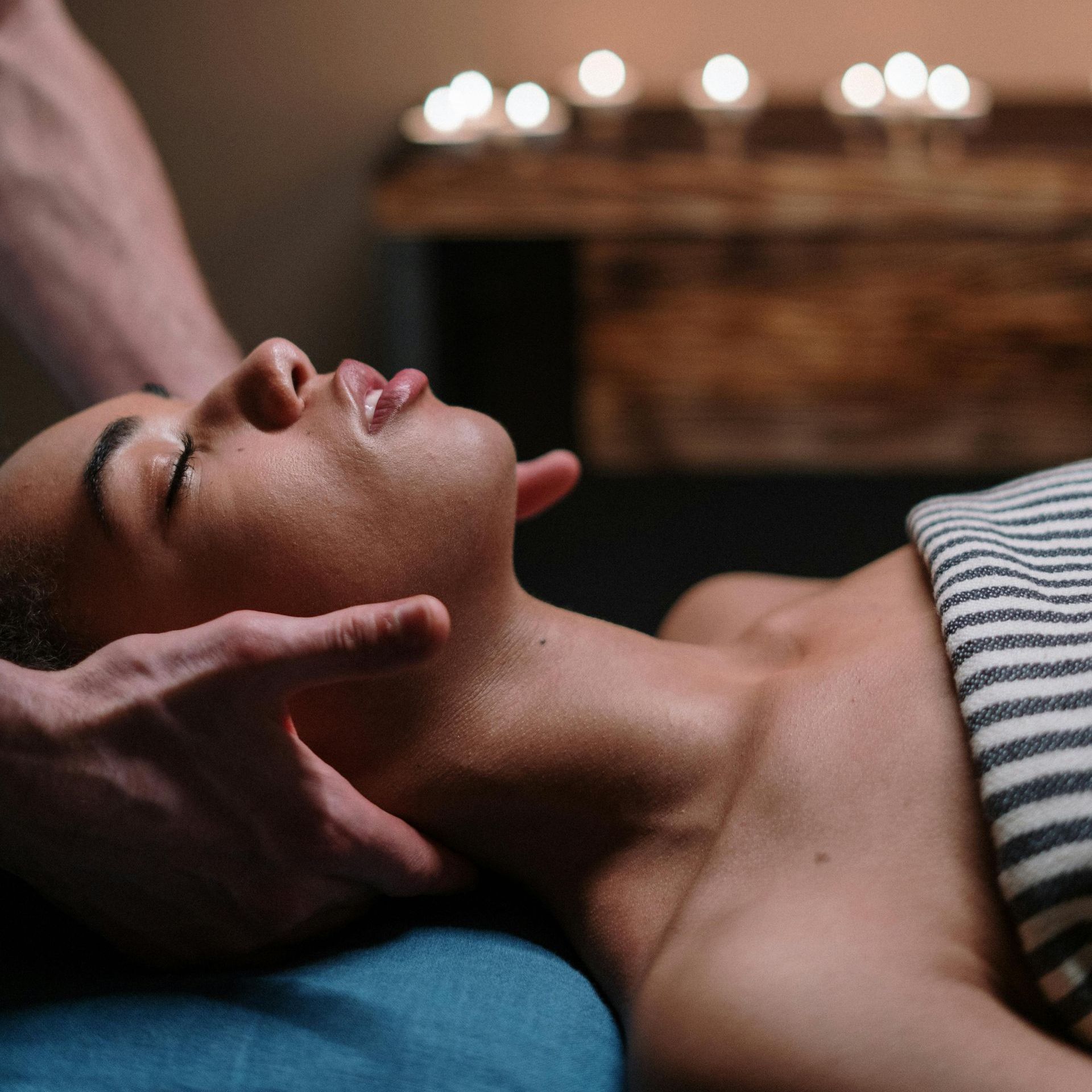 A woman is getting a massage in a spa with candles in the background.