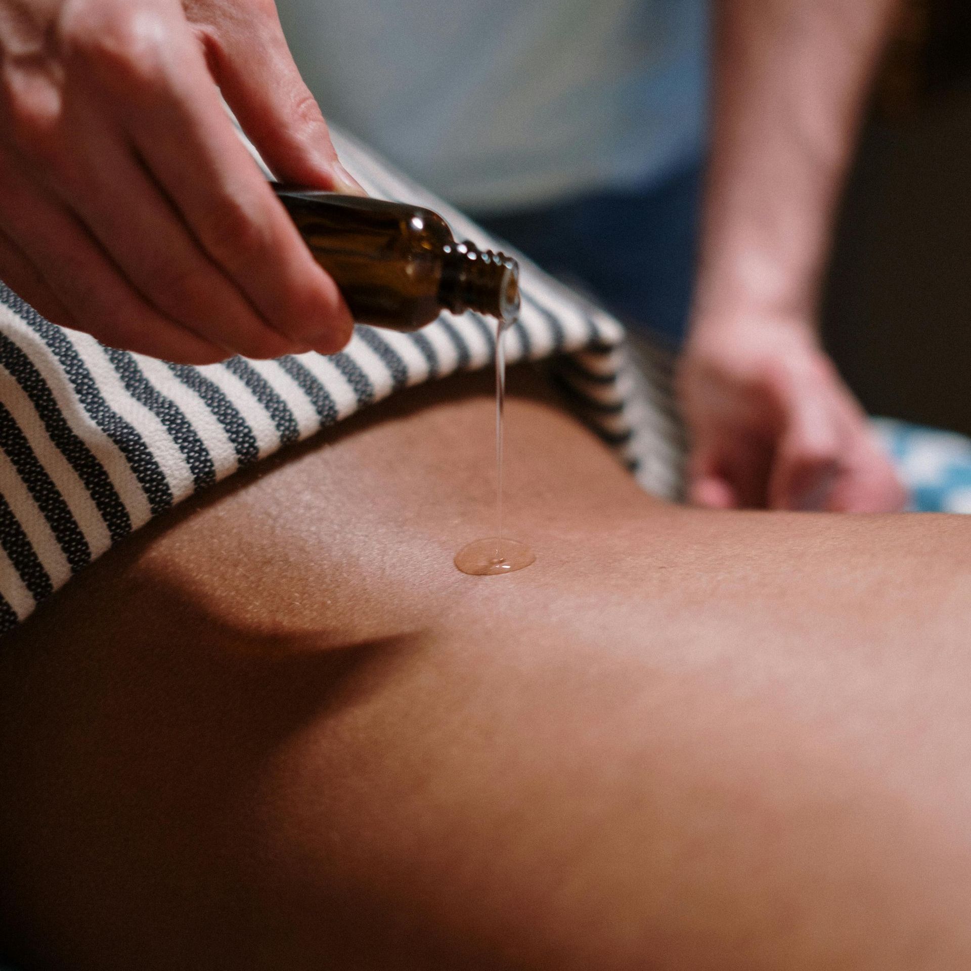 A person is applying oil to another person 's back