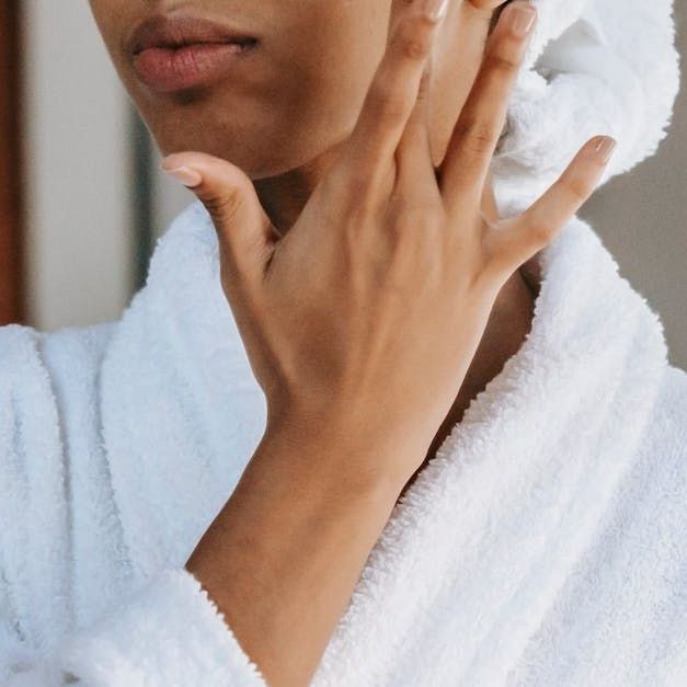 Sandstone Therapeutic Massage / A woman is touching her face in the mirror.