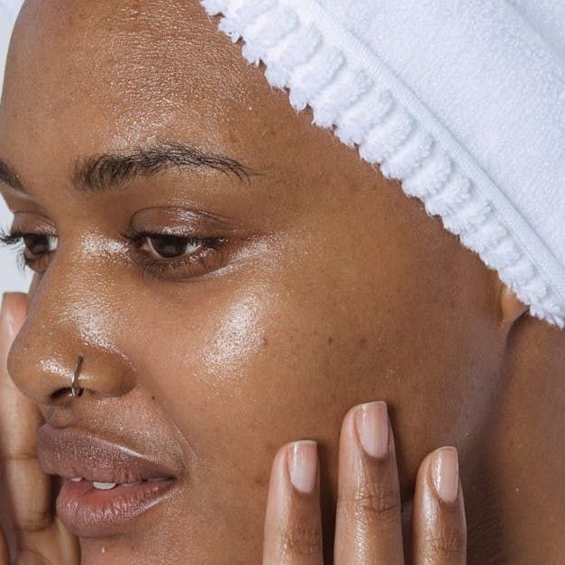 Sandstone Therapeutic Massage /A woman with dreadlocks is wearing a white turtleneck and looking up.