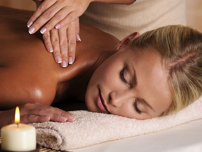 A woman is getting a massage in a spa next to a candle.