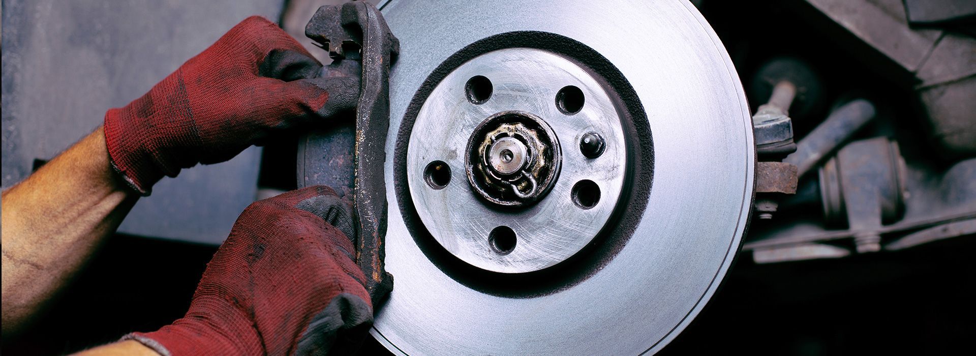a person wearing red gloves is working on a brake disc