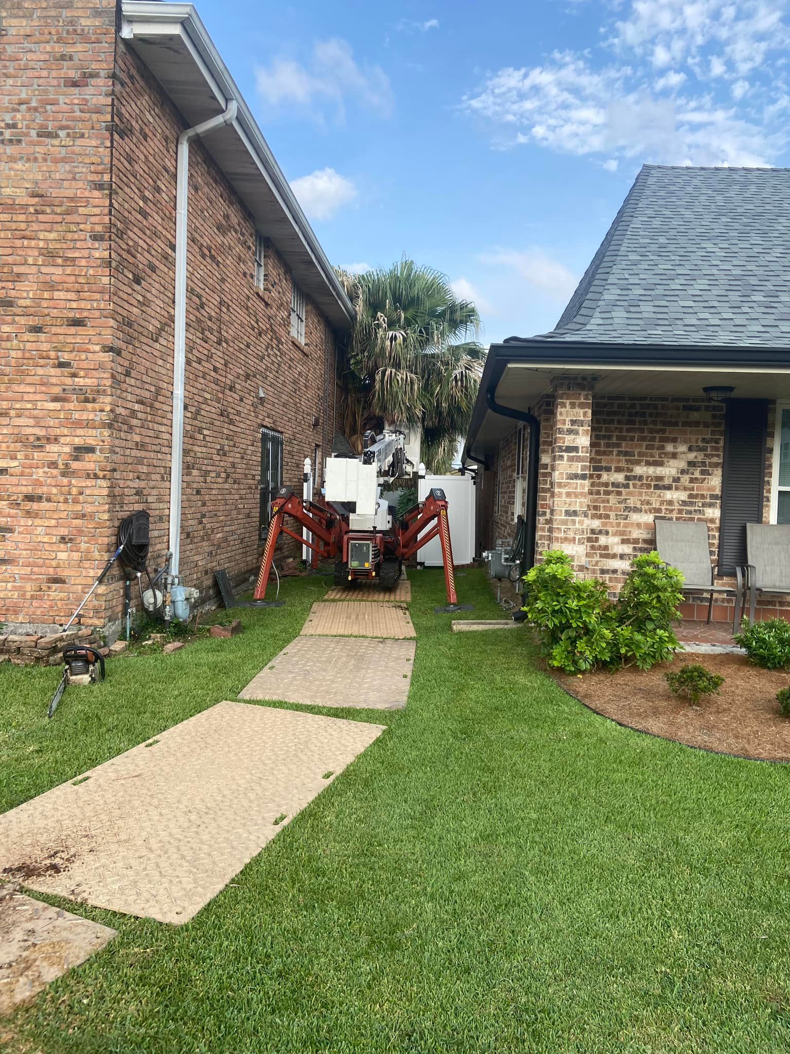 A lawn mower is parked in front of a brick house.