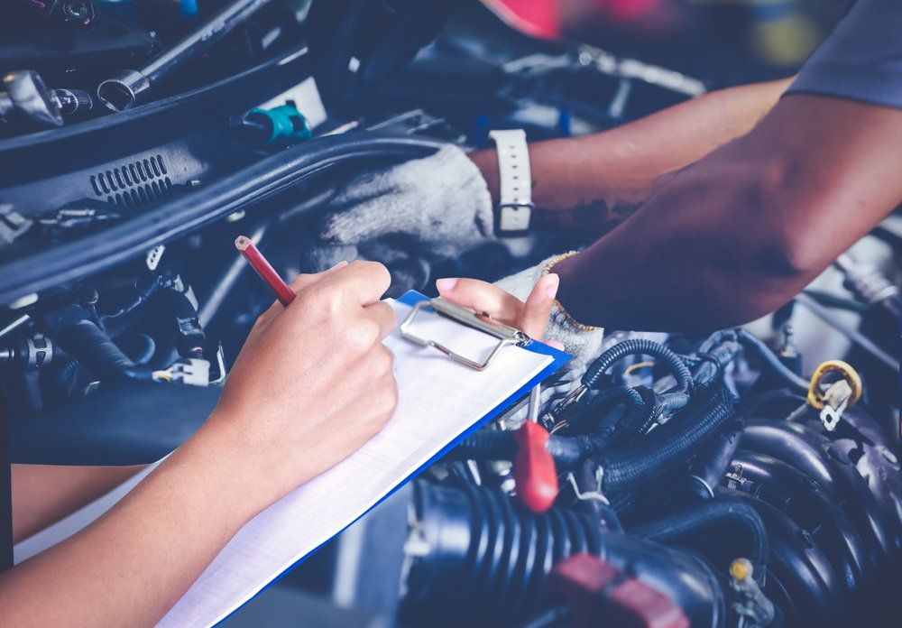A Man Is Working On A Car Engine While A Woman Writes On A Clipboard — Hastings Diesel Service In Wauchope, NSW
