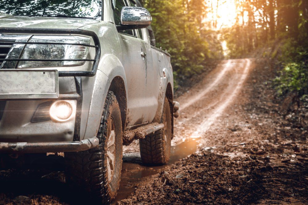 A Pickup Truck Is Driving Down A Muddy Dirt Road — Hastings Diesel Service In Wauchope, NSW