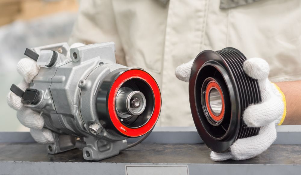 A Person Is Holding A Compressor And A Pulley In Their Hands — Hastings Diesel Service In Wauchope, NSW
