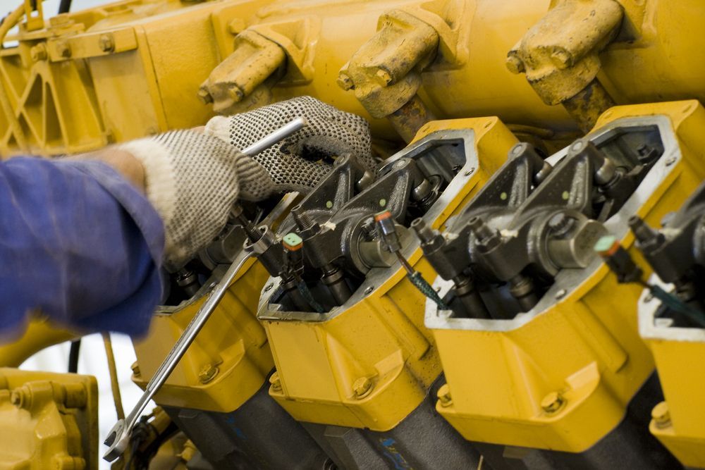 A Man Is Working On A Yellow Engine With A Wrench — Hastings Diesel Service In Laurieton, NSW
