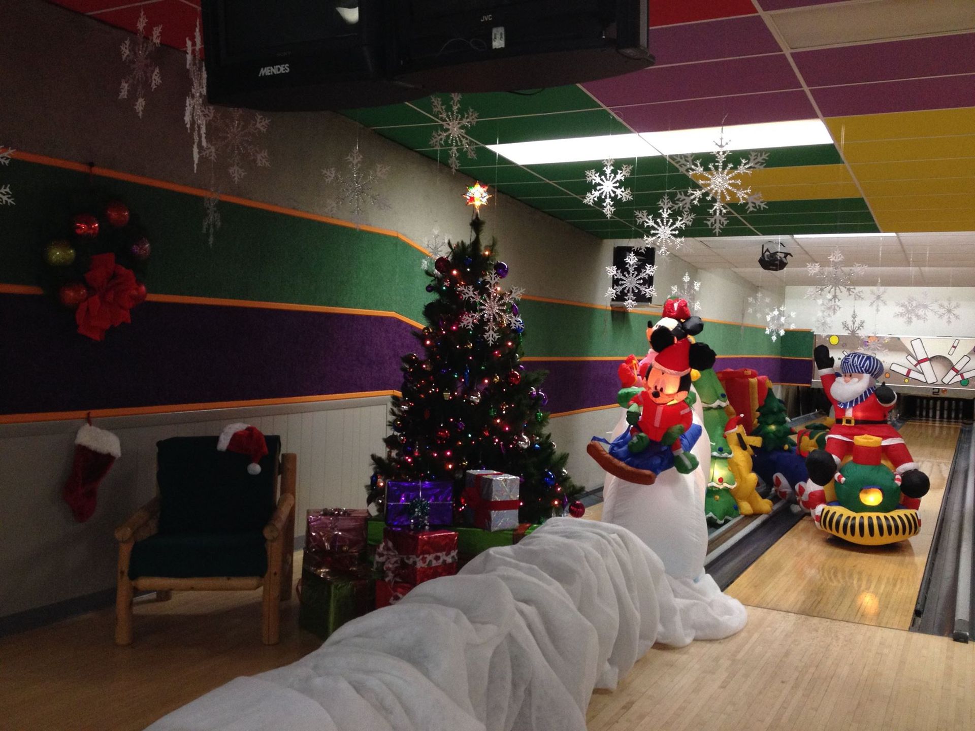 A bowling alley decorated for christmas with a train and a christmas tree