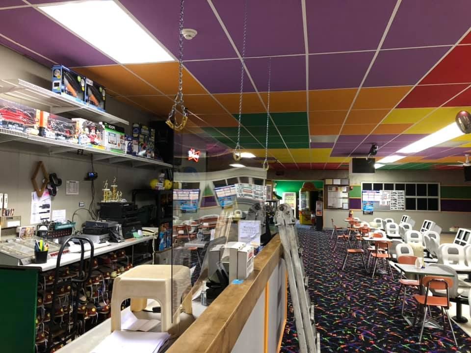A bowling alley with a rainbow colored ceiling and tables and chairs.