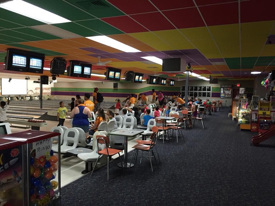 A bowling alley with people sitting at tables and chairs