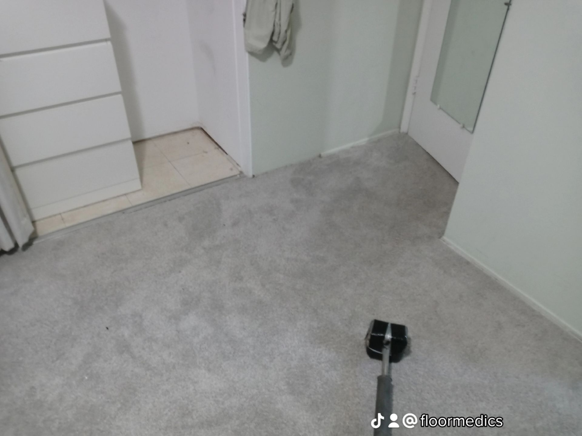 A selfie stick is sitting on a carpeted floor in a room