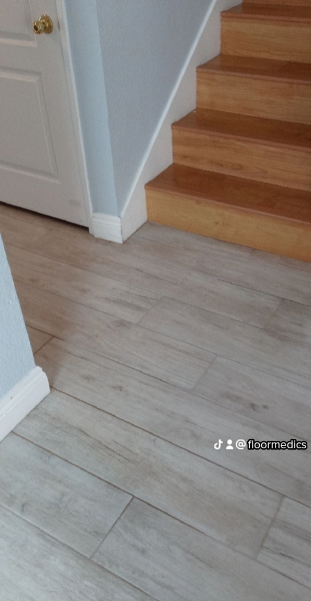 A wooden staircase with a white tile floor next to it.