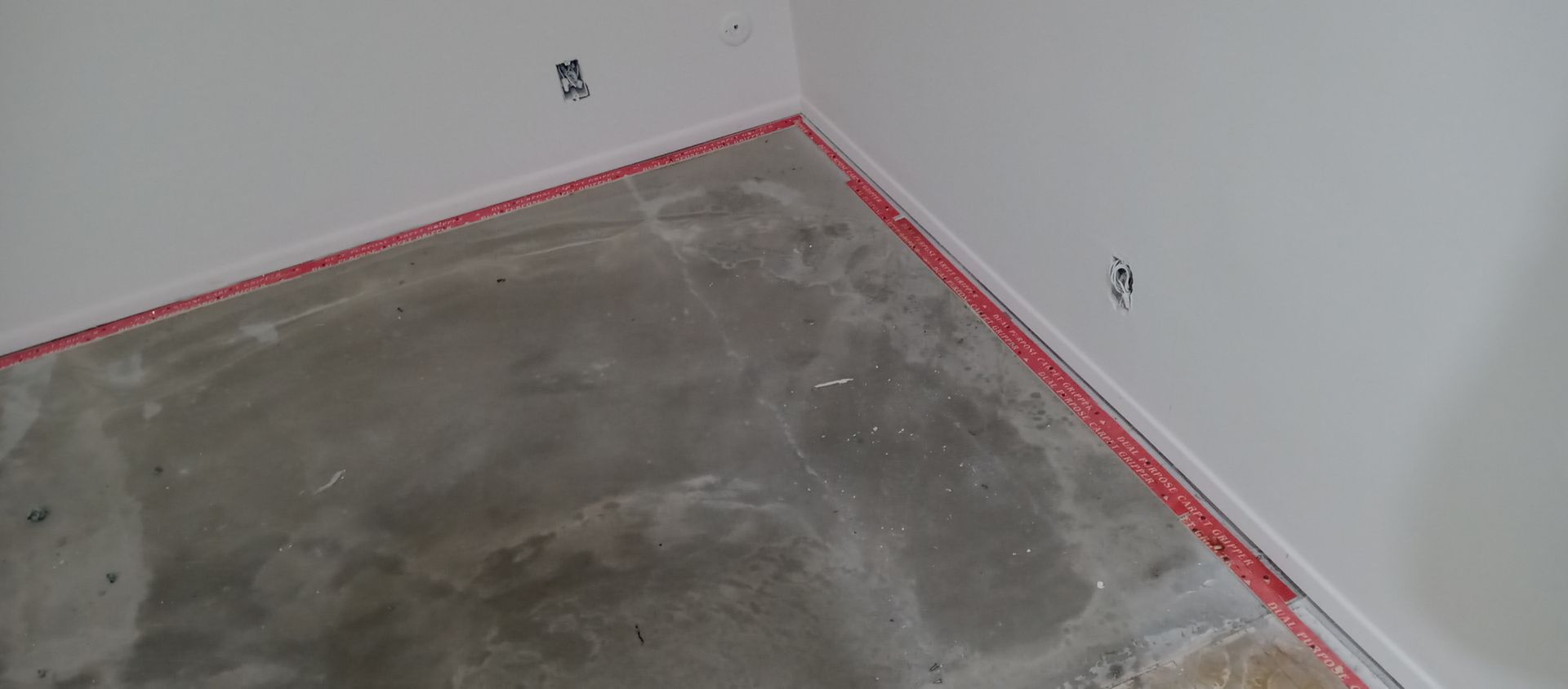 A corner of a room with a concrete floor and white walls.