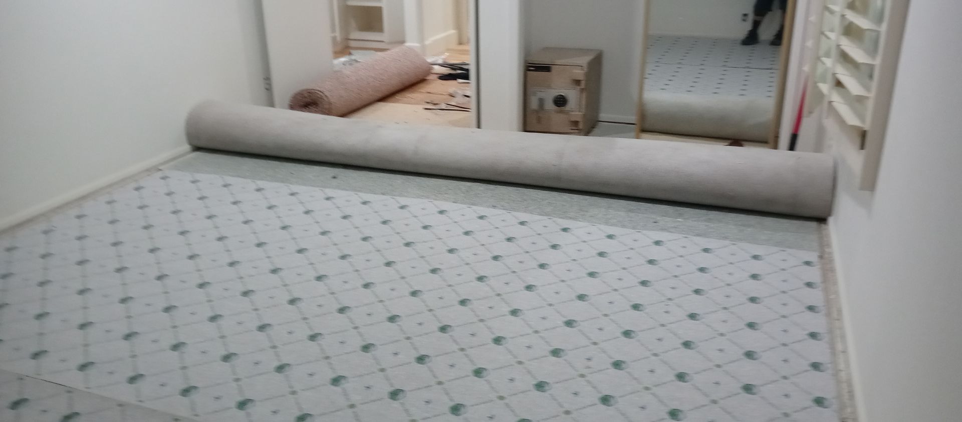 A roll of carpet is being rolled up in a room.