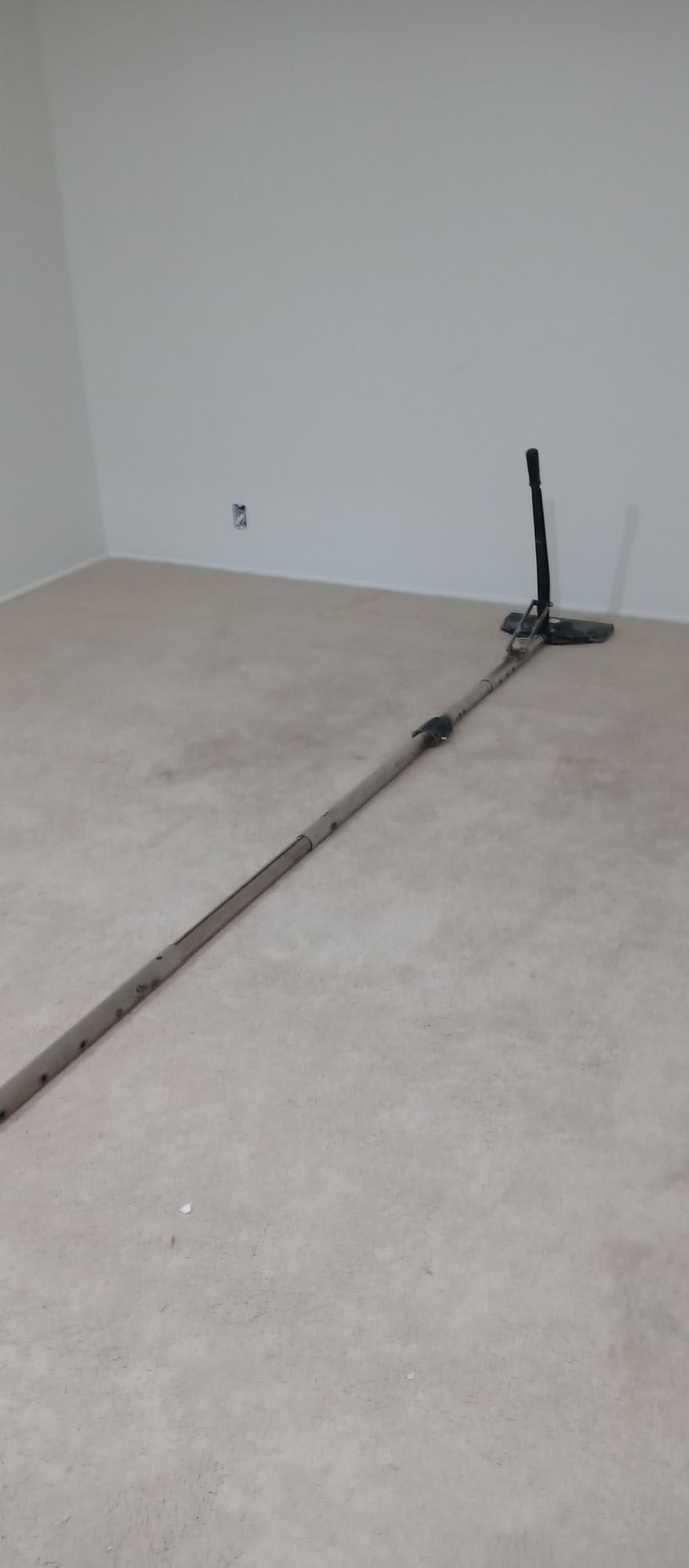 An empty room with a mop on the floor.