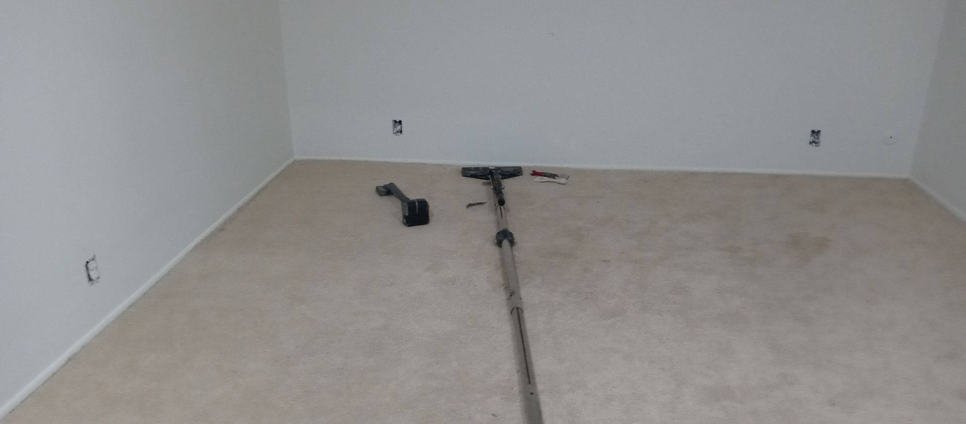 An empty room with a vacuum cleaner on the floor.