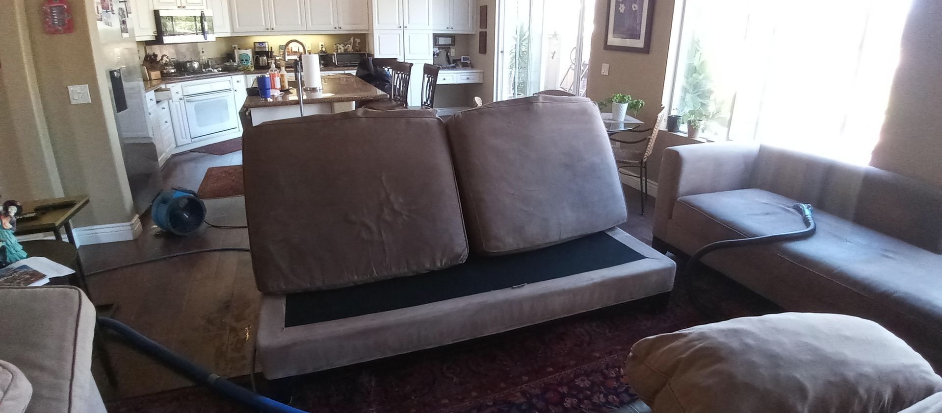 A living room with a couch and chairs and a vacuum cleaner.