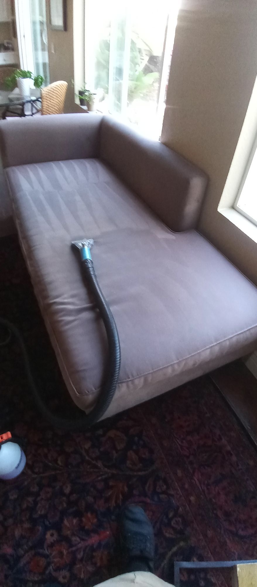 A vacuum cleaner is being used to clean a couch in a living room.
