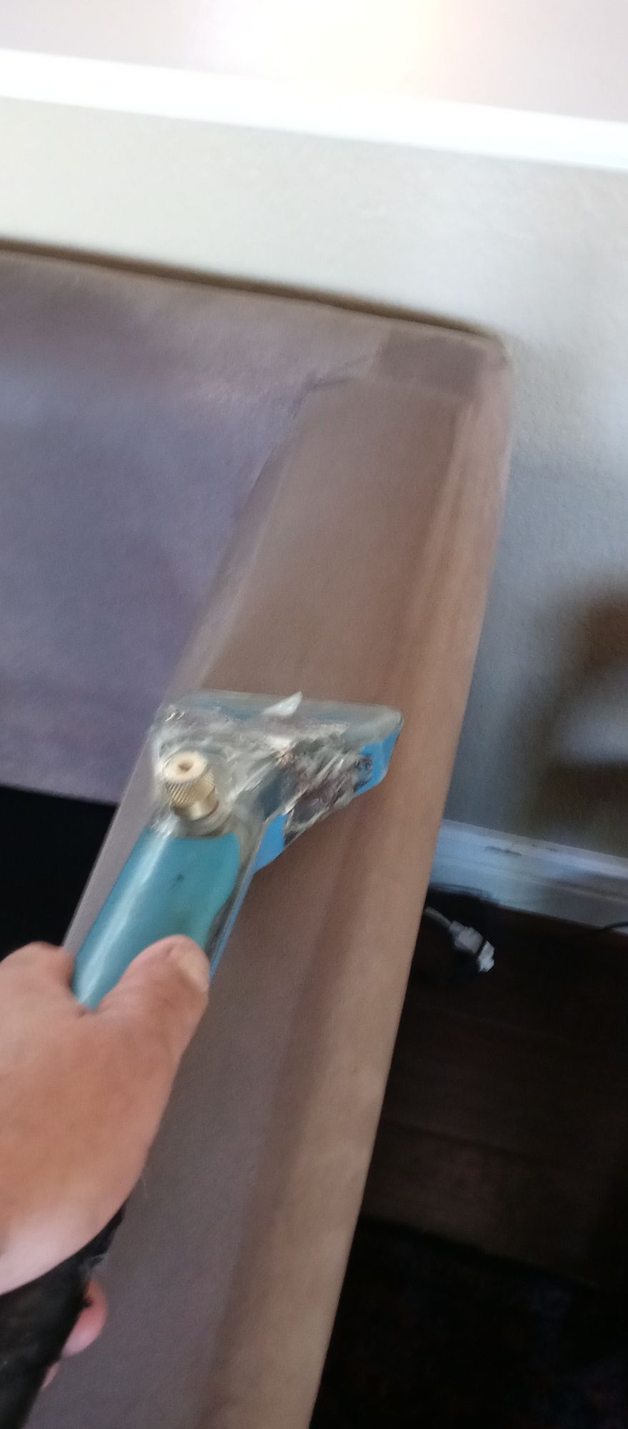A person is cleaning a couch with a vacuum cleaner.