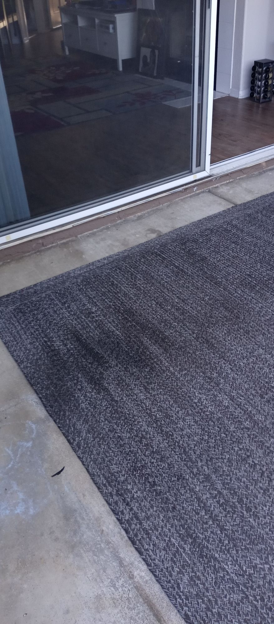 A rug is sitting on the ground in front of a sliding glass door.