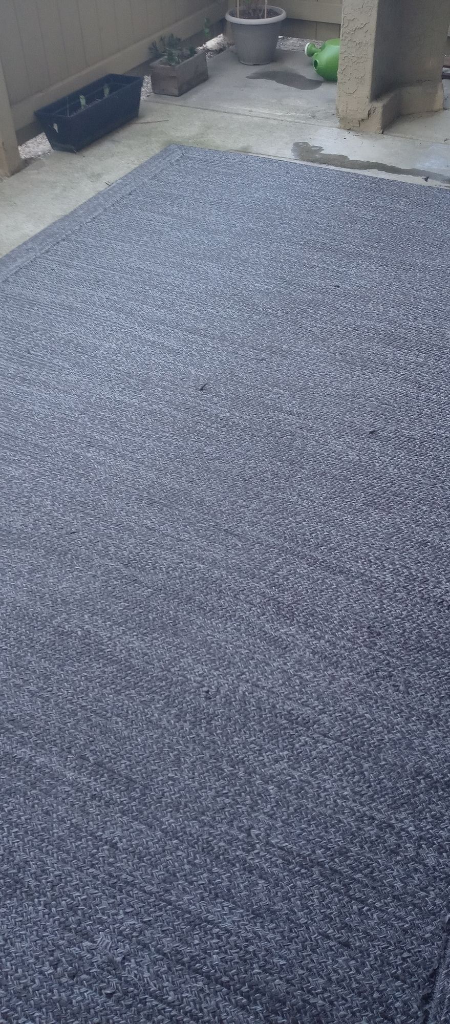 A large gray rug is sitting on the floor in a room.