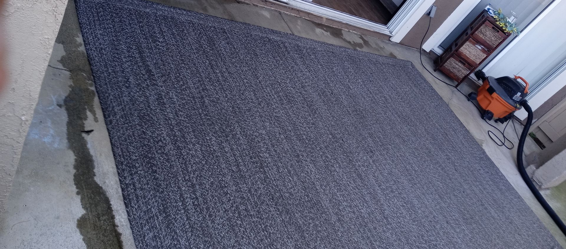 A vacuum cleaner is sitting on a concrete floor next to a door.