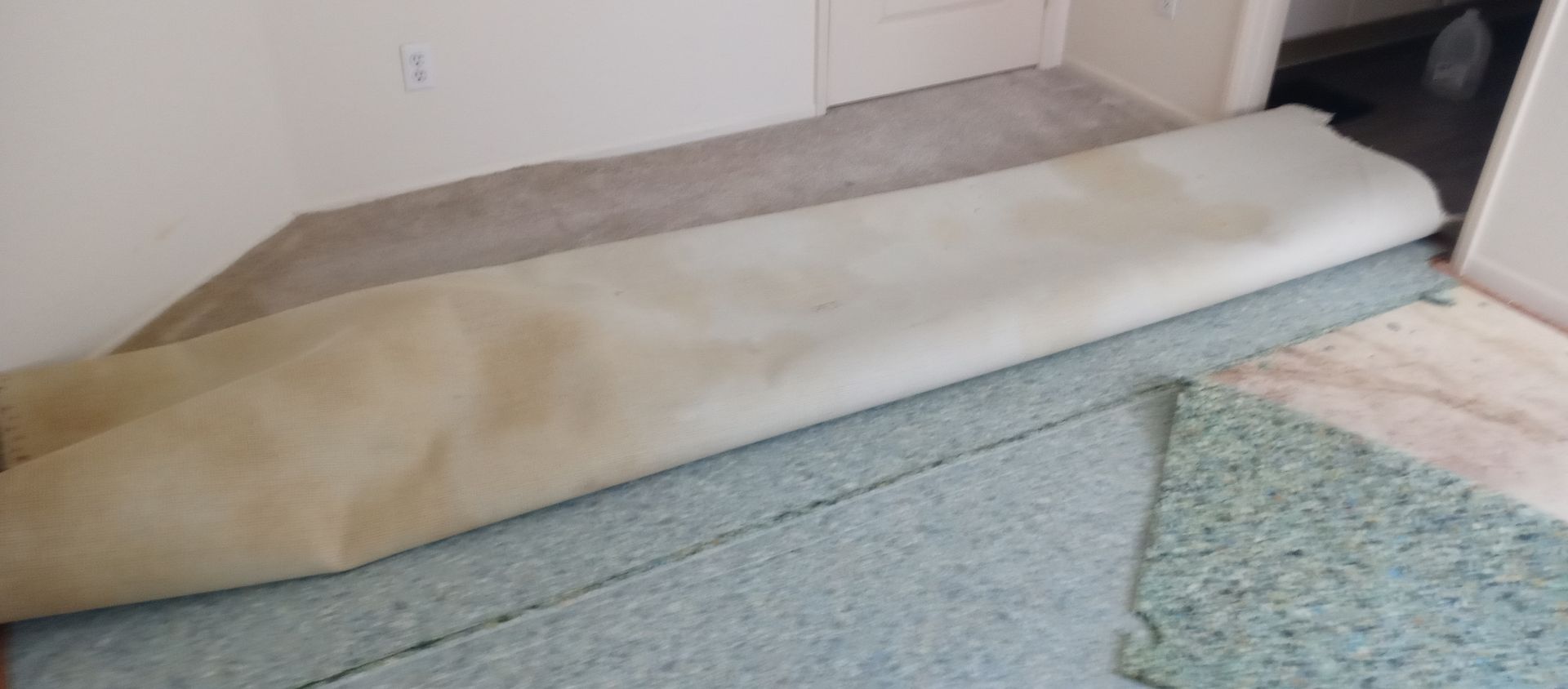 A piece of carpet is laying on the floor next to a door.