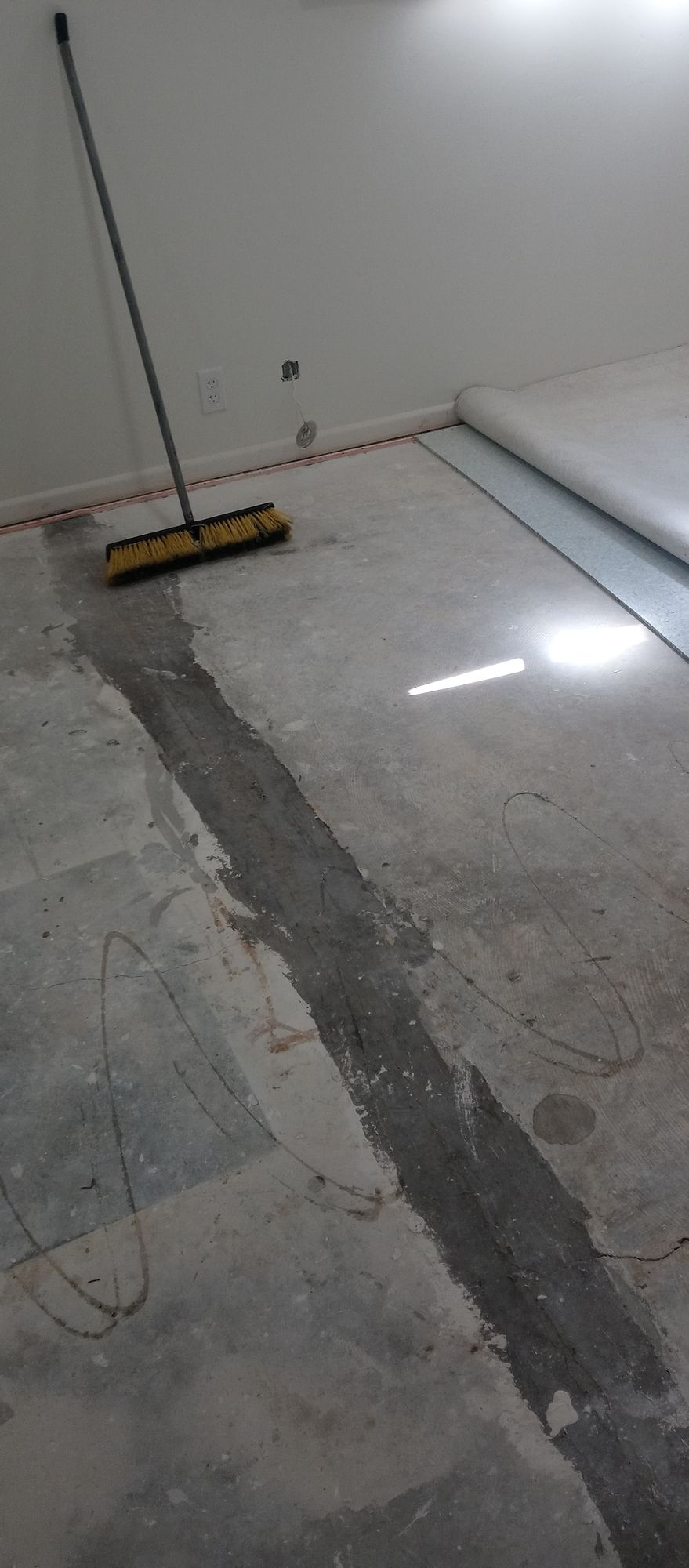 A broom is sitting on the floor of a room.