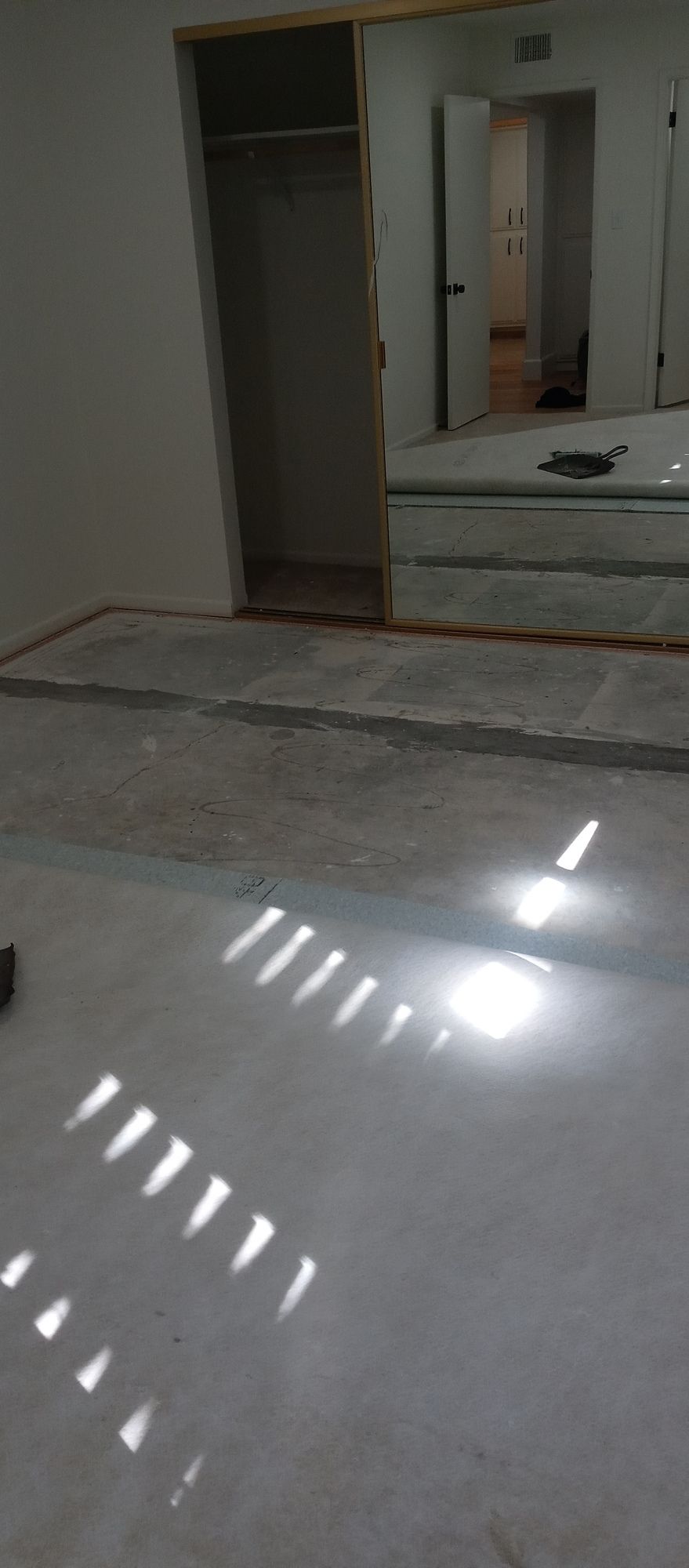 A room with a white floor and a mirror on the wall.