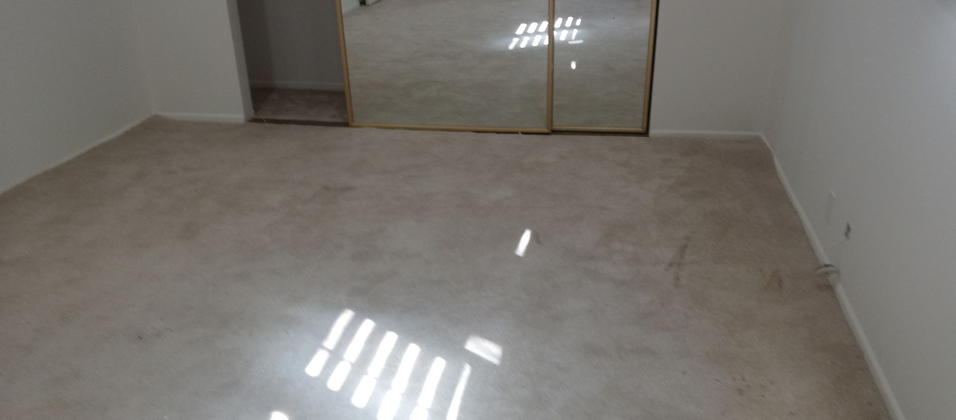 An empty room with a carpeted floor and sliding glass doors.