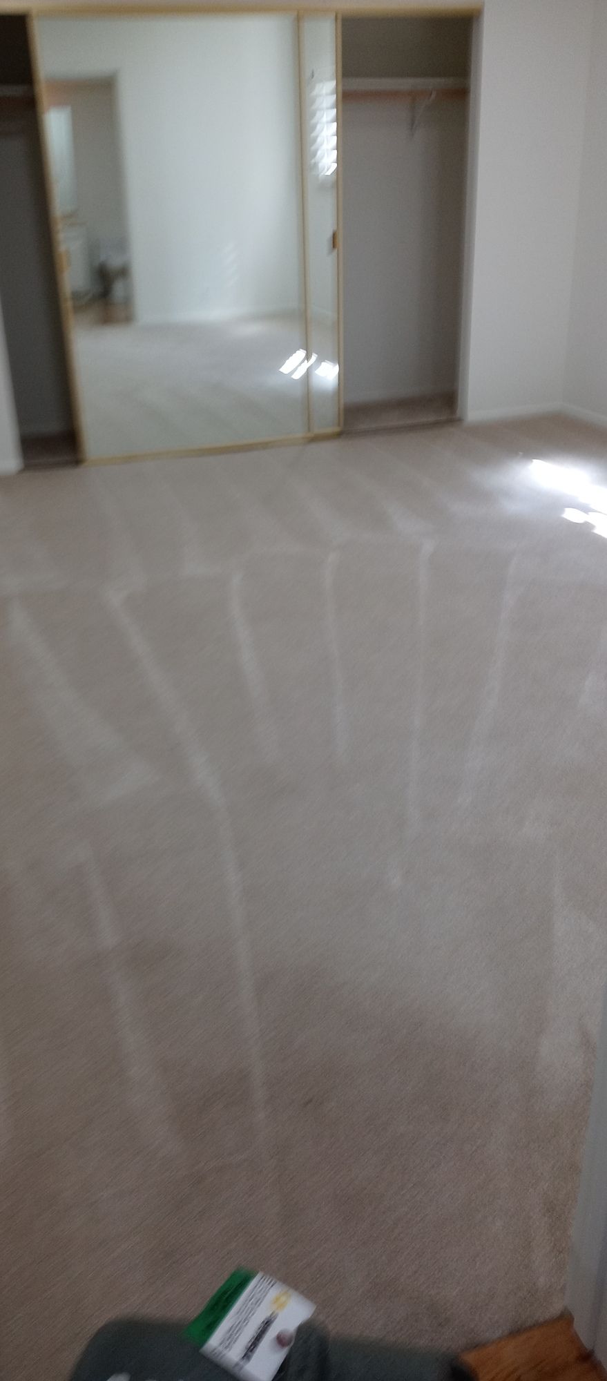 A large empty room with a carpeted floor and sliding glass doors.